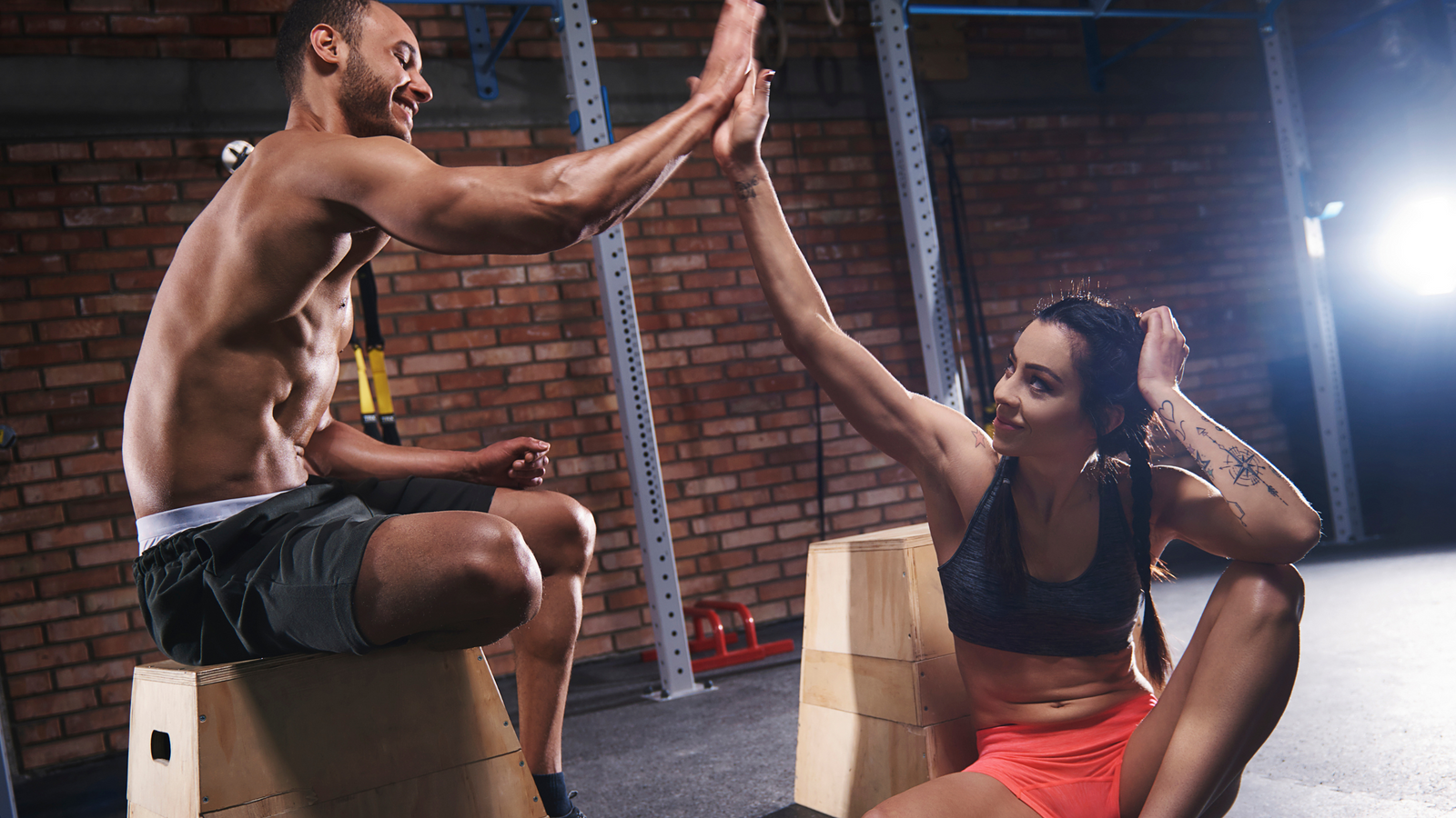 Coppia di atleti in palestra dopo l’allenamento che si dà il cinque, simbolo di motivazione, energia e risultati con la creatina