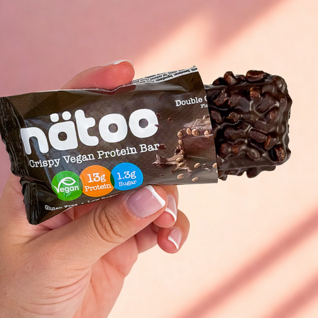 Barretta proteica vegana Nätoo Double Chocolate tenuta in mano – snack proteico tascabile low sugar